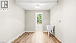 Laundry room with light wood-style floors, washer hookup, and beamed ceiling - 