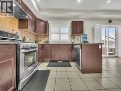 Kitchen with stainless steel appliances, ventilation hood, decorative backsplash, healthy amount of natural light, and recessed lighting - 
