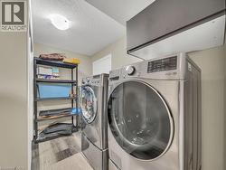 Washroom with a textured ceiling, light wood-style flooring, and washing machine and clothes dryer - 