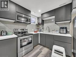 Kitchen with appliances with stainless steel finishes, gray cabinets, backsplash, and light wood-style floors - 
