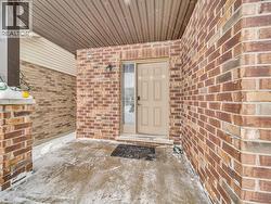 View of exterior entry featuring brick siding and a patio area - 