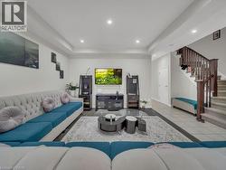 Living room featuring a raised ceiling, stairs, and recessed lighting - 