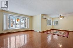 Empty room featuring hardwood / wood-style floors, a wall mounted AC, and ceiling fan - 