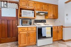 Kitchen featuring white appliances, light countertops, brown cabinetry, and under cabinet range hood - 