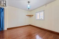 Unfurnished room featuring wood-type flooring and baseboards - 