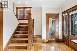 Entryway with ornamental molding, light wood finished floors, and stairs - 