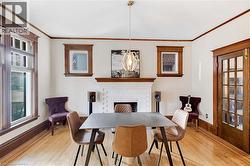 Dining space with a brick fireplace, light wood-type flooring, and ornamental molding - 