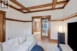 Living room with coffered ceiling, beam ceiling, wood finished floors, and french doors - 