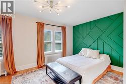 Bedroom featuring an accent wall, radiator, light wood-style flooring, and a chandelier - 