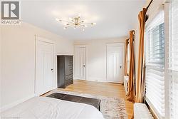Bedroom featuring radiator heating unit, light wood-style floors, a chandelier, and multiple closets - 
