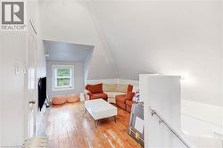 Sitting room featuring light wood finished floors, an upstairs landing, and lofted ceiling - 