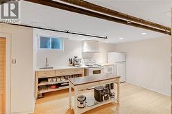 Kitchen featuring light countertops, white appliances, light wood-style floors, under cabinet range hood, and recessed lighting - 