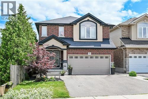 Two-story residence featuring a brick and stucco facade, a prominent arched window on the second level, a covered front entryway, and an attached two-car garage with paneling - 71 Jessica Street, Hamilton, ON - Outdoor