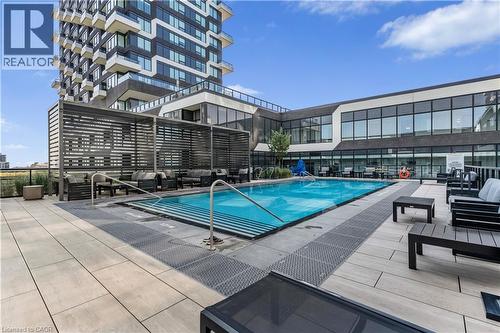 Resort-style pool complemented by a patio and inviting outdoor hangout area - 297 Oak Walk Drive Unit# 2407, Oakville, ON - Outdoor With In Ground Pool