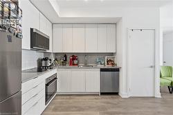 Kitchen featuring stainless steel appliances, light wood-style flooring, tasteful backsplash, and modern cabinets - 