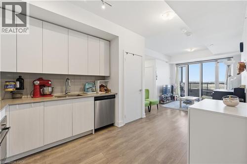 Modern kitchen with stainless steel appliances, light wood-style flooring, stylish backsplash, and sleek cabinetry - 297 Oak Walk Drive Unit# 2407, Oakville, ON - Indoor Photo Showing Kitchen