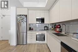 Bright, modern kitchen with stainless steel–finish appliances, light stone countertops, and sleek cabinetry - 