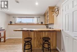 Bar area featuring light wood-style flooring and glass insert cabinets - 