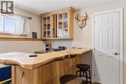 Indoor wet bar featuring glass insert cabinets and butcher block countertops - 