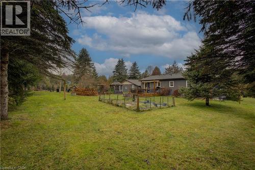 View of grassy yard featuring a wooden deck and view of wooded area - 230 Saugeen Street, Grey Highlands, ON - Outdoor