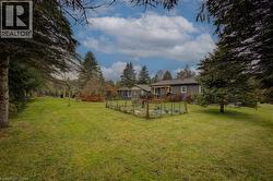 View of grassy yard featuring a wooden deck and view of wooded area - 