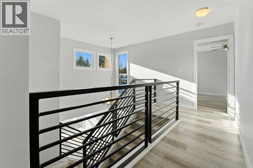 A bright stairwell with a modern black metal railing and additional windows connects the main floor and second level - 4 Pardue Close, Red Deer, AB - Indoor Photo Showing Other Room