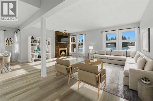 The spacious living room is filled with natural light from abundant south-facing windows and features a cozy wood-burning fireplace - 4 Pardue Close, Red Deer, AB - Indoor Photo Showing Living Room With Fireplace