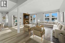 The spacious living room is filled with natural light from abundant south-facing windows and features a cozy wood-burning fireplace - 