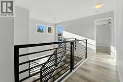 A bright stairwell with a modern black metal railing and additional windows connects the main floor and second level - 