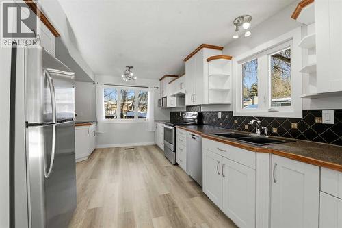 The galley-style kitchen showcases stylish cabinetry, a pantry, two sinks, and upgraded stainless steel appliances - 4 Pardue Close, Red Deer, AB - Indoor Photo Showing Kitchen With Double Sink