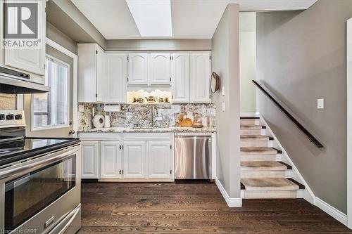 Kitchen with appliances with stainless steel finishes, light stone countertops, white cabinetry, tasteful backsplash, and dark wood finished floors - 359 Pepper Drive, Burlington, ON - Indoor Photo Showing Kitchen
