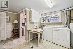 Washroom with cabinet space, washer and clothes dryer, ornamental molding, and water heater - 