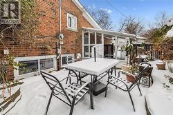 Snow covered patio with outdoor dining area and a sunroom - 