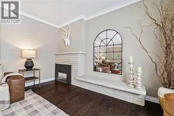 Living room with hardwood / wood-style floors, crown molding, and a brick fireplace - 