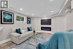 Living room with a glass covered fireplace, wood finished floors, and recessed lighting - 