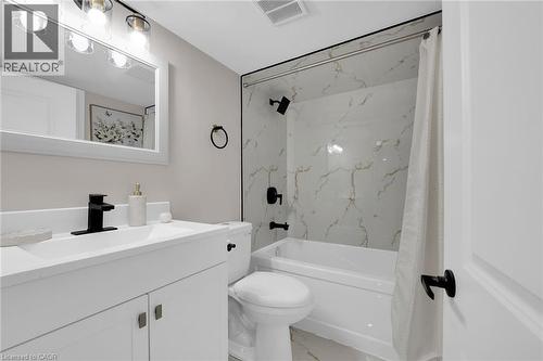 Bathroom with light marble finish floors, vanity, and shower / bath combination with curtain - 174 East 34Th Street, Hamilton, ON - Indoor Photo Showing Bathroom