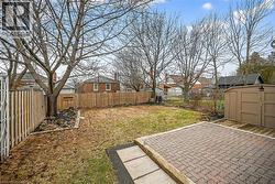 Fenced backyard featuring a residential view, a storage unit, and a patio area - 