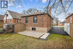 Rear view of house featuring brick siding, a shed, a chimney, a patio area, and roof with shingles - 