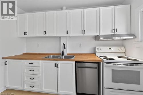 Kitchen with electric range, white cabinetry, light countertops, and stainless steel dishwasher - 77 Barton Street E Unit# 2, Hamilton, ON - Indoor Photo Showing Kitchen With Double Sink