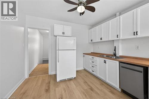 Kitchen with freestanding refrigerator, dishwasher, butcher block countertops, white cabinetry, and light wood-type flooring - 77 Barton Street E Unit# 2, Hamilton, ON - Indoor Photo Showing Kitchen With Double Sink