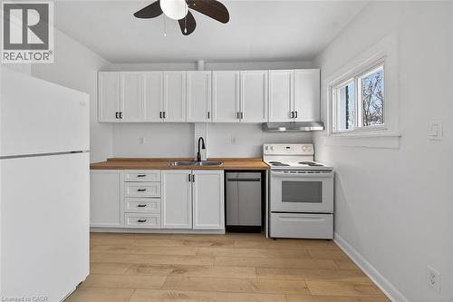 Kitchen featuring white appliances, white cabinets, a ceiling fan, and light wood-type flooring - 77 Barton Street E Unit# 2, Hamilton, ON - Indoor Photo Showing Kitchen With Double Sink