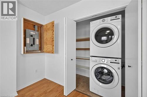 Washroom featuring estacked washer and dryer, light wood finished floors, and electric panel - 77 Barton Street E Unit# 2, Hamilton, ON - Indoor Photo Showing Laundry Room
