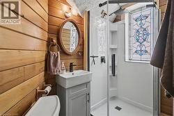 Full bathroom featuring a stall shower, wood walls, and vanity - 