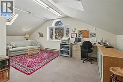 Office with a skylight, lofted ceiling, a baseboard heating unit, and light carpet - 