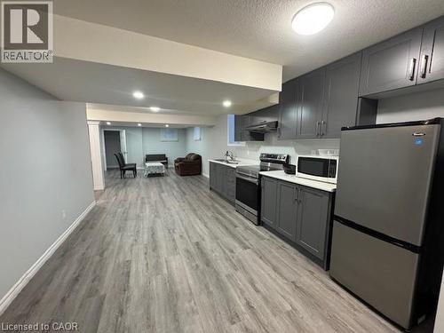 Kitchen featuring stainless steel appliances, light countertops, light wood-style floors, a textured ceiling, and open floor plan - 509 St Moritz Avenue Unit# Lower, Waterloo, ON - Indoor Photo Showing Kitchen