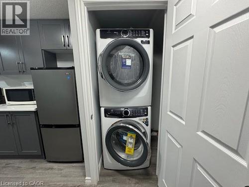 Washroom with estacked washer and dryer, light wood-type flooring, and a textured ceiling - 509 St Moritz Avenue Unit# Lower, Waterloo, ON - Indoor Photo Showing Laundry Room