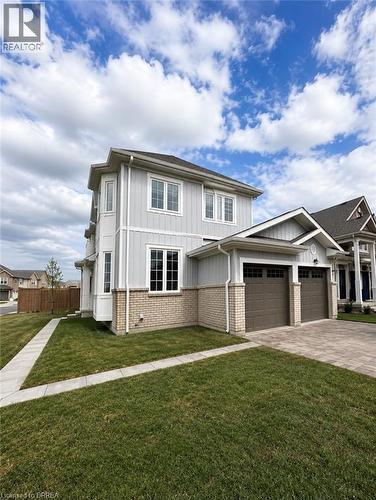 Two-story residence featuring light gray siding with white trim, a brick facade, and a two-car garage with paneled doors - 22 Todd Crescent, Dundalk, ON - Outdoor With Facade
