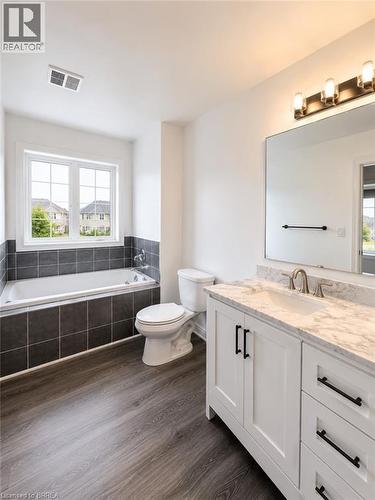 Bathroom featuring a white vanity with a marble-finish countertop and brushed nickel faucet, a large rectangular mirror, and a modern light fixture - 22 Todd Crescent, Dundalk, ON - Indoor Photo Showing Bathroom