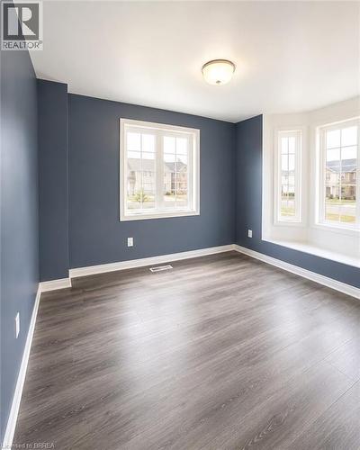 Spacious room featuring wood-finish flooring, a contemporary bay window, white trim, a flush mount ceiling light, and blue-painted walls - 22 Todd Crescent, Dundalk, ON - Indoor Photo Showing Other Room