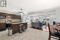 Kitchen featuring stainless steel electric range oven, dark brown cabinets, open floor plan, a kitchen island, and a fireplace - 